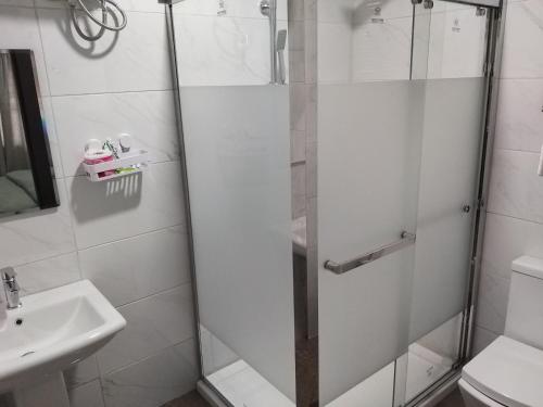 a glass shower door in a bathroom with a sink at MITOS LUXURY SUITES -Somosu in Lagos