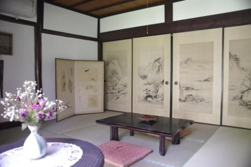 a room with a table and a vase of flowers at Guesthouse Higashi Fujitatei in Shinonsen