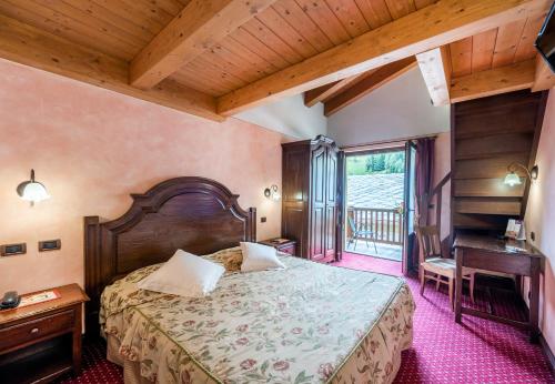 a bedroom with a large bed and a desk at Hotel L' Aiglon in Champoluc