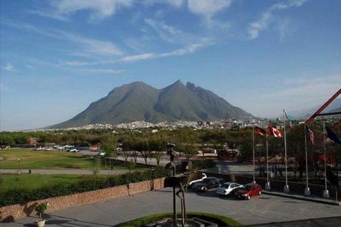 Holiday Inn Monterrey-Parque Fundidora, an IHG Hotel في مونتيري: اطلاله على جبل فيه سيارات متوقفه في موقف