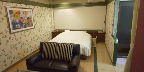 um quarto com uma cama e uma cadeira de couro em Hotel Oasis (Adult Only) em Fukaya
