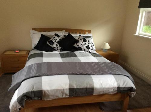 łóżko z czarno-białymi kocami i poduszkami w obiekcie The Firs w mieście Ashford