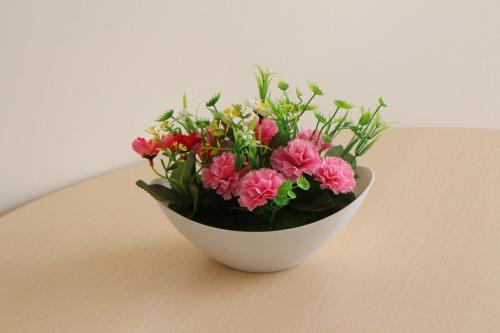 a white bowl filled with pink flowers on a table at Апарт отель Welcome in Taldykorgan