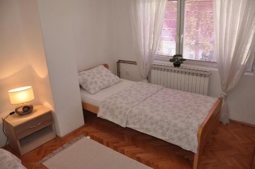 a small bedroom with a bed and a window at Apartmani Nedim in Dubrave Gornje