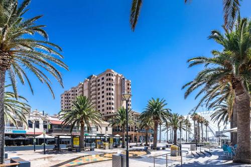 a street with palm trees and a tall building at Hi 5 Glenelg Studio Apartment in Glenelg