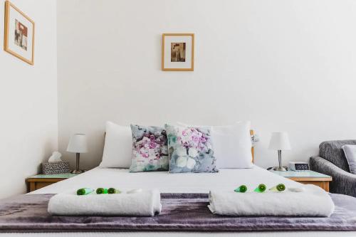 uma cama branca com almofadas e fruta verde em Hi 5 Glenelg Studio Apartment em Glenelg