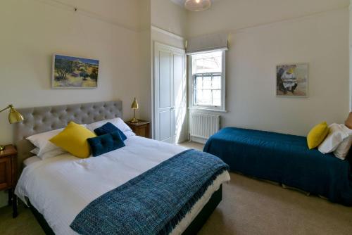 a bedroom with two beds with blue and yellow pillows at Elm Tree Lodge Beechworth in Beechworth
