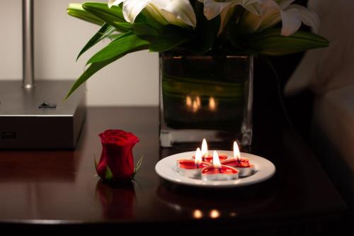 a table with a plate with candles and a vase with flowers at Savoy Park Hotel Apartments in Dubai