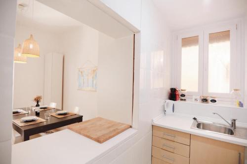 eine weiße Küche mit einem Waschbecken und einem Tisch in der Unterkunft Amparito Apartment - Casc Antic in Tarragona