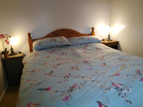 a bed with a blue comforter with flowers on it at Garden Cottage in Sleaford