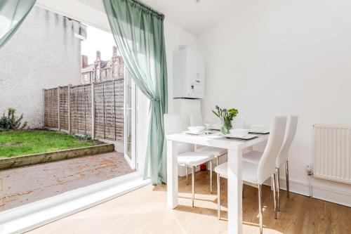 un comedor blanco con mesa y ventana en Serviced Apartment /Excel/ Olympic city/ O2 arena, en Londres