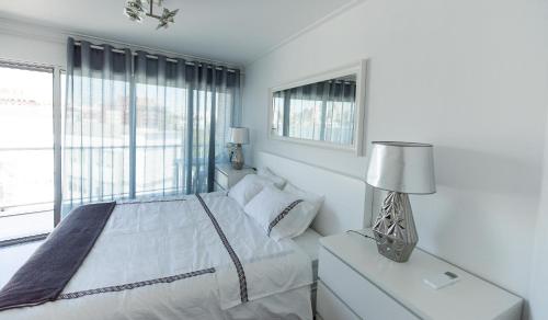 a white bedroom with a bed and a window at Charming Apartment with Balcony & Pool in Lisbon