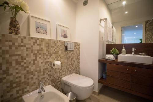 a bathroom with a white toilet and a sink at Charming Apartment with Balcony & Pool in Lisbon