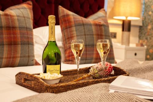 a bottle of champagne and two glasses on a bed at The Roseate Edinburgh - Small Luxury Hotels of the World in Edinburgh