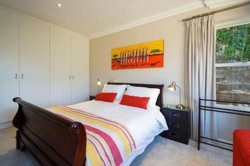 a bedroom with a bed with red pillows and a window at Sandpiper's Nest - Hout Bay in Hout Bay