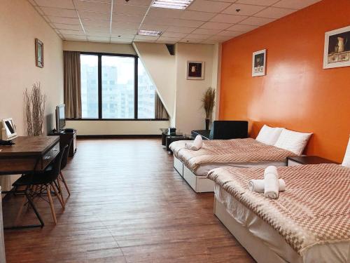 a room with two beds and a desk and a desk at Neo Sky Hotel in Kaohsiung