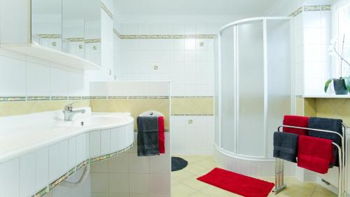 a white bathroom with a sink and a shower at Apartmány Monty in Karlovy Vary