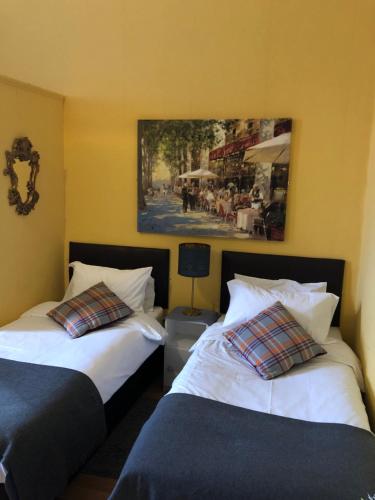 two beds in a room with a painting on the wall at Counan Guest House in Edinburgh