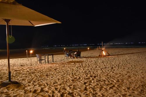 a beach with an umbrella and chairs and a bonfire at Handun Villas in Talalla