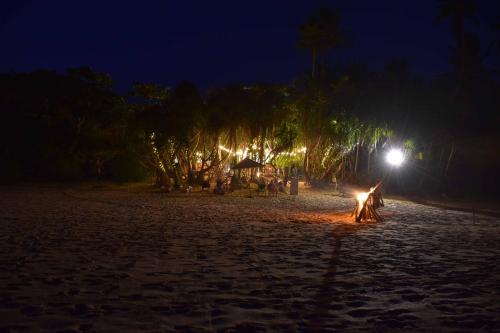 a person sitting around a fire on a beach at night at Handun Villas in Talalla