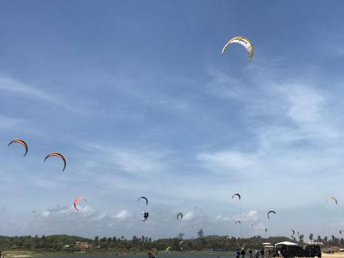 a group of people flying kites in the sky at Pousada & Food 3 Abelhas in Cumbuco