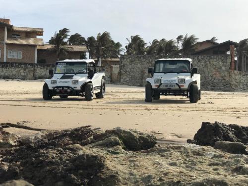two white jeeps driving on a dirt road at Pousada & Food 3 Abelhas in Cumbuco