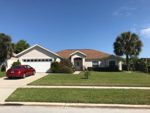 a house with a red car parked in a driveway at Robin's Nest in Orlando