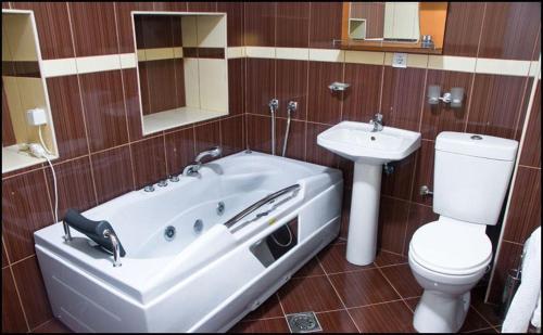 a bathroom with a tub and a toilet and a sink at Hotel Leder in Kočani