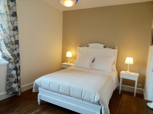 a bedroom with a white bed with two lamps at Le Clos des ifs in Thiétreville