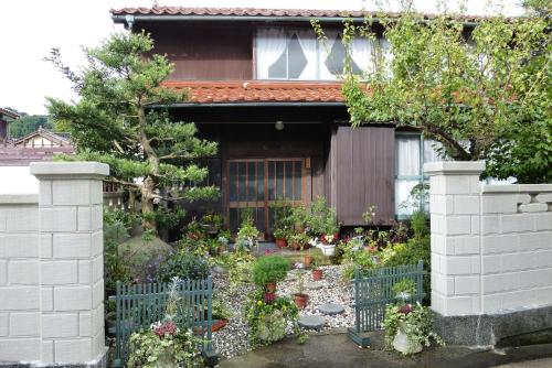 a garden in front of a house with a fence at Guesthouse Higashi Fujitatei in Shinonsen