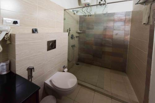 a bathroom with a toilet and a shower with a glass door at Zizina Otis Resort in Guwahati