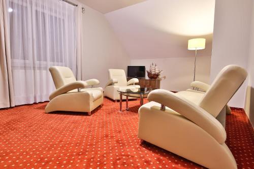 a living room with white chairs and a television at Hotel Kantoria in Tarnów