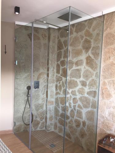 a shower in a room with a stone wall at aznalmara loft rural in Benaocaz