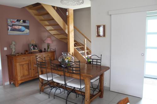 une salle à manger avec une table en bois et un escalier dans l'établissement Le Clos Louisiane, à Saint-Loup-Hors
