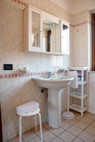 a bathroom with a white sink and a stool at Le Ville di Porto Ada in Pizzo