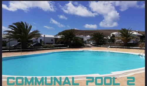duży błękitny basen z palmami i domami w obiekcie Love for Lanzarote holidays house w mieście Playa Blanca