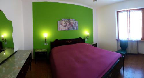 een groene slaapkamer met een bed met een paarse deken bij Il Giardino di Marina in Santa Maria Maggiore