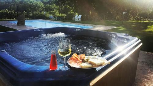 a hot tub with a plate of food and a glass of wine at Agriturismo Podere Del Lepre in San Quirico