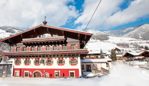 a large red and white building in the snow at Hotel Flatscher in Stuhlfelden