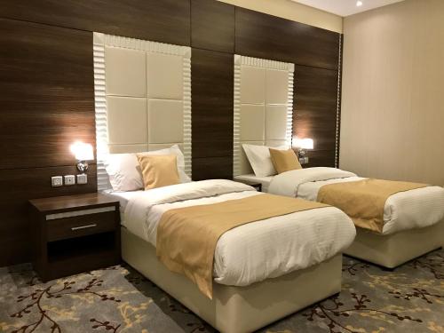 two beds in a hotel room with two lamps at Ayan Hotel in Riyadh