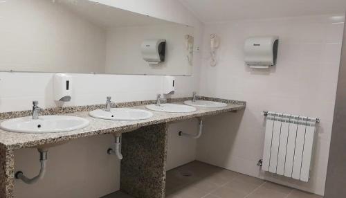 a public bathroom with three sinks and a mirror at Loriga Hostel - Feel Nature in Loriga