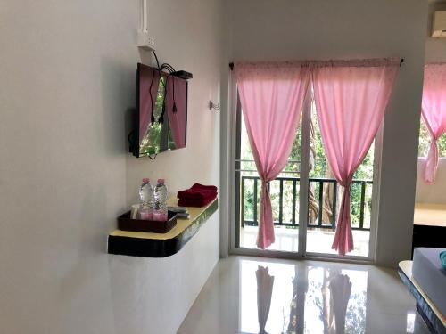 a room with a large window with pink curtains at chillchillsangkhlaburi โรงแรมชิลชิลสังขละบุรี in Sangkhla Buri