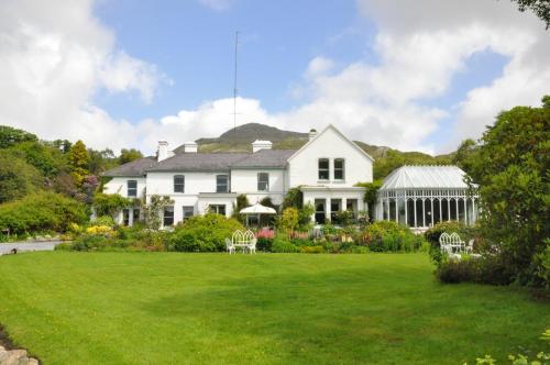 a large white house with a garden and lawn at Cashel House Hotel in Roundstone