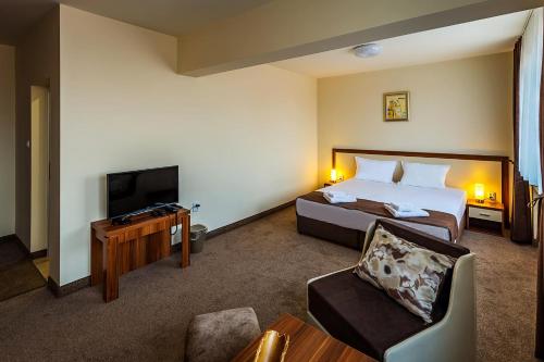 a hotel room with a bed and a flat screen tv at Family Hotel Bulgaria in Kharmanli