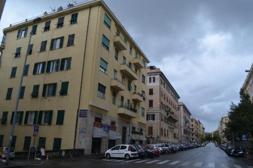 a large yellow building on a street with cars parked at Il Genovino in Genova