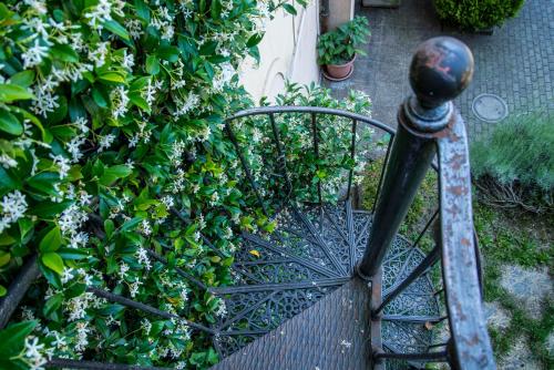 a metal bench in a garden next to a bush at Ostello Montebello - Bellinzona Youth Hostel in Bellinzona