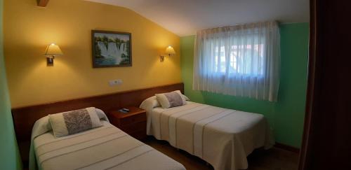 two beds in a room with green and yellow at Pensión Toranda in Niembro