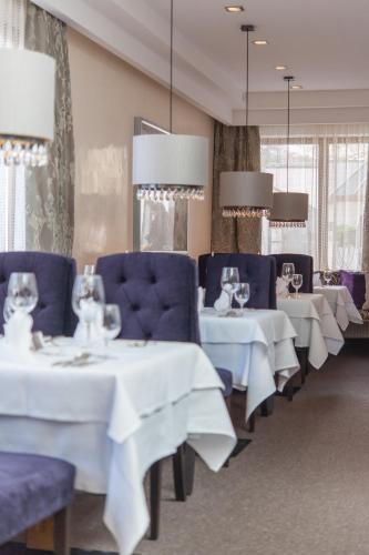 a restaurant with white tables and blue chairs and tablesearcher at Hotel Alpina deluxe in Obergurgl