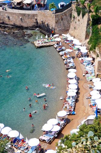 a beach with umbrellas and people in the water at Elegance East Hotel in Antalya
