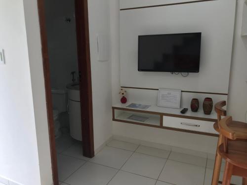 a bathroom with a television on a white wall at Casa Carmelo #18 in Porto Seguro